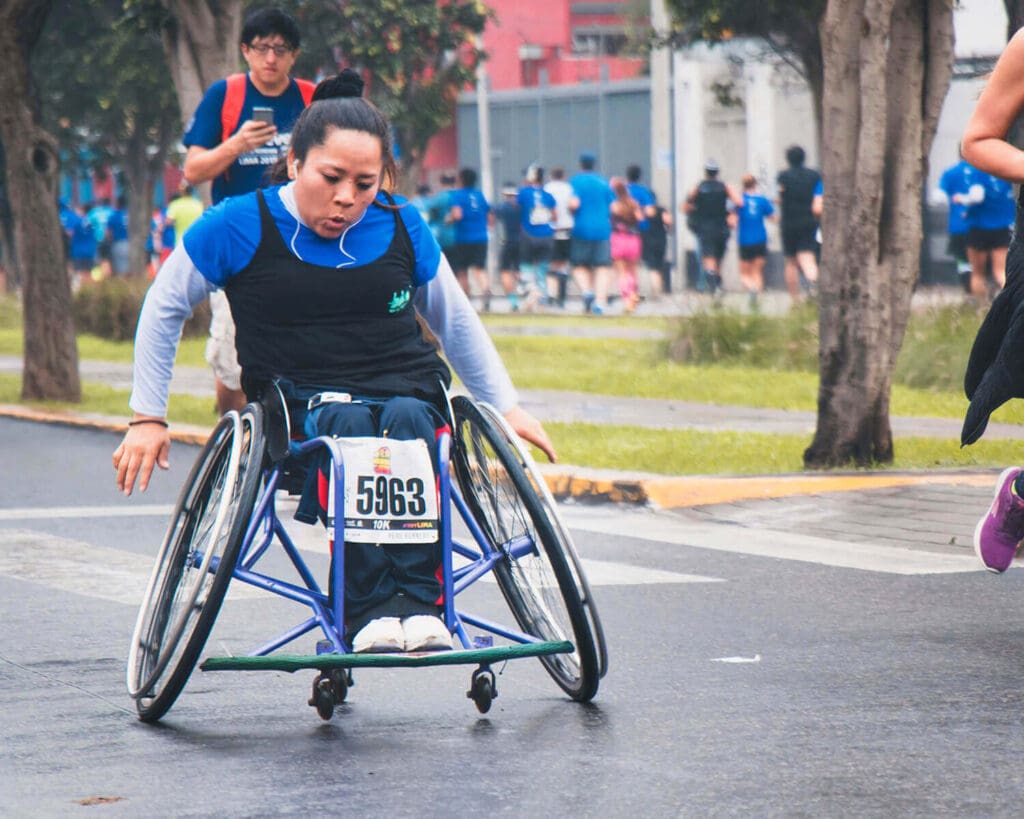 Woman in blue shirt in wheelchair competing in race to benefit a charity nonprofit. Nonprofit fundraising events like this can boost awareness, but ROI and marketing budget must be monitored, too.
