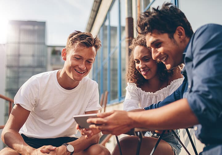 Smiling, diverse people looking at a smartphone as image used to illustrate creative marketing and advertising effectiveness