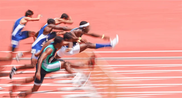 men jumping hurdles and running on a race track